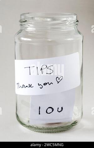 A tips jar with a label reading Tips Thank you but with only an IOU in the bottom. Stock Photo