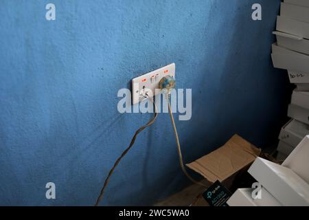Extremely bad electrical practice with wires pushed into a plug socket in Bo, Sierra Leone, Africa. Stock Photo