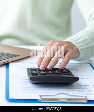 Woman working in office using calculator and laptop. Finance accounting Stock Photo