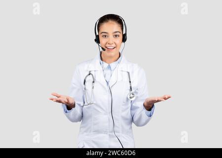 An approachable european doctor wearing a headset and a white lab coat gesturing with open hands Stock Photo
