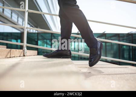 Cropped of male legs as unrecognizable businessman walking upstairs outside Stock Photo