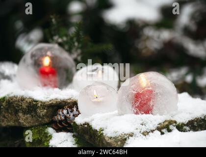 Handmade winter decoration with ice global lantern and candles in the evening in the snow covered garen. Winter outdoor decoration concept Stock Photo