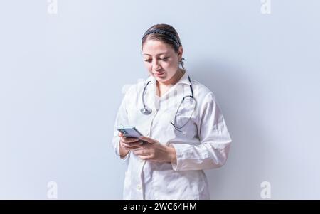 Young female doctor with telephone isolated. Smiling female doctor using phone on isolated background Stock Photo