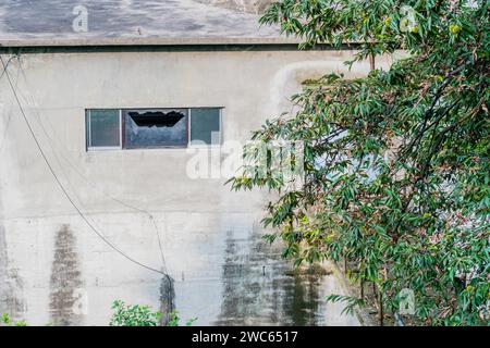 Broken window in exterior wall of building Stock Photo