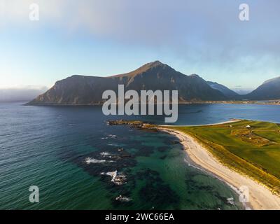 Aerial view of Lofoten at sunset, with spectacular mountains, deep fjords and blue sky with patchy fog. White sand beach. The beach of Skagsanden. Stock Photo