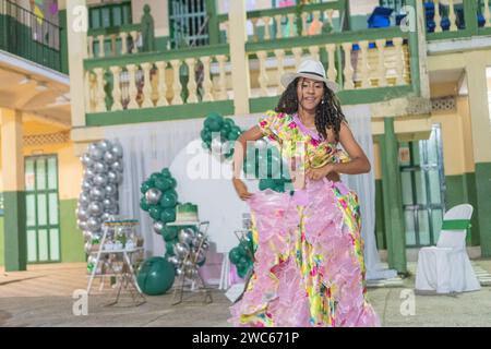 Radiant woman performing Cumbia dance, her floral dress swirling, topped with a stylish white hat. Stock Photo