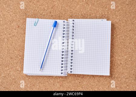 Notepad with ballpoint pen on a cork board. Stock Photo