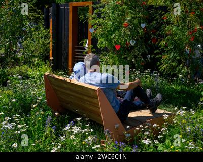 Constructing Minds show garden competition entry visitors (couple of people sitting relaxing) - RHS Tatton Park Flower Show 2023, Cheshire England UK Stock Photo