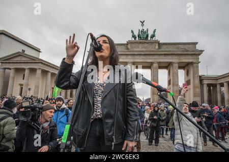 Berlin, Germany. 14th Jan, 2024. On the stage in Berlin, Duezen Tekkal, a renowned German author, journalist, filmmaker, and activist of Kurdish-Yezidi descent, delivered a compelling speech. Born on September 2, 1978, in Hannover, Tekkal has established herself as a significant voice in various fields, including journalism, human rights advocacy, and social entrepreneurship. In an unparalleled show of solidarity, the streets of Berlin on January 14, 2024, echoed with the voices of 25,000 protesters as they converged at Pariser Platz in the shadow of the iconic Brandenburg Gate. The demonstr Stock Photo