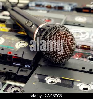 Square photo with a microphone close-up on a background of old audio cassettes. Stock Photo