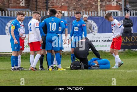 A Warrington Rylands player lies injured on the pitch during a match against Whitby Town at The Hive Stadium, Warrington, Cheshire, England Stock Photo