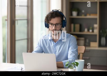 Man in headphones sit at desk laptop makes video call Stock Photo