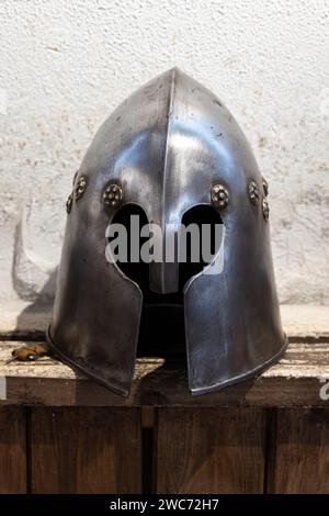 Iron helmet of medieval knight is on a wooden shelf Stock Photo