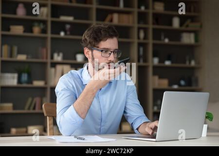 Serious business man holding smartphone talk to client on speakerphone Stock Photo