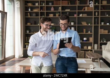 Twins brothers using digital tablet standing in living room Stock Photo