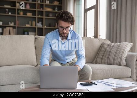 Serious man sit on sofa do accounting work from home Stock Photo