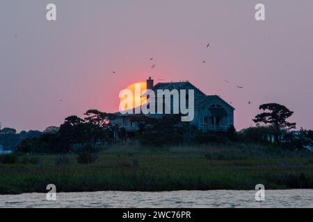 A charming, cozy cottage perched atop a picturesque hill, bathed in the warm golden hues of a breathtaking sunset Stock Photo