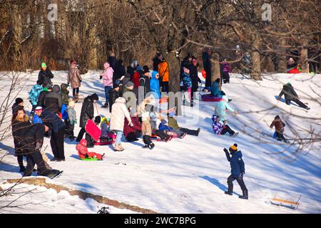 Happy family father, daughter and son are sledding in snow. Happy winter holidays. Stock Photo