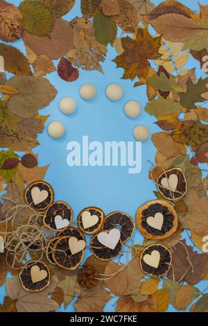 Autumn concept frame background and wooden hearts. Colorful leaf frame with dry citrus fruits slices of oranges and wooden hearts Stock Photo