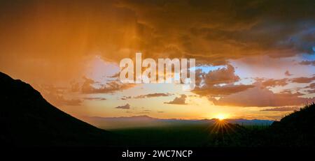 Capturing a sunset starburst at Gates Pass amidst monsoon rains, with the striking silhouettes of Saguaro Cacti. Stock Photo