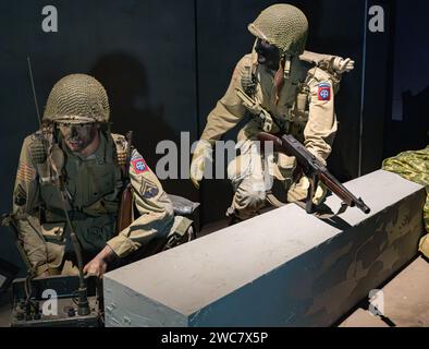 Detail of two American airbone soldiers entrenched behind a wall in World War II, radio operator calling reinforcements and soldier withmachine gun Stock Photo