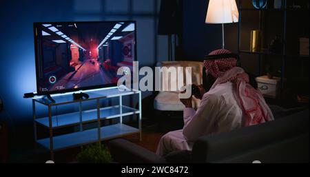 Arab gamer feeling gutted after losing singleplayer action videogame level, being outsmarted by enemies. Upset man placing hands on head in frustration after seeing game over screen Stock Photo