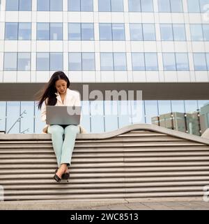 Young Asian business woman working with laptop in a financial district Stock Photo
