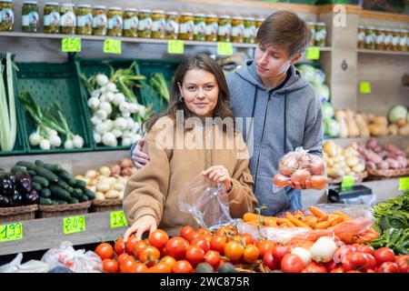 Young married couple buys tomatoes in grocery store Stock Photo