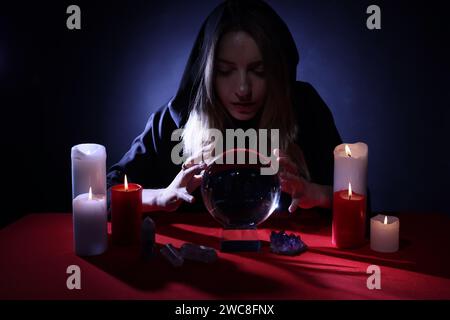 Soothsayer using crystal ball to predict future at table in darkness. Fortune telling Stock Photo