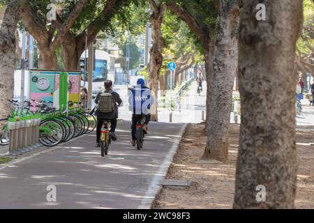 A cyclist and a delivery boy riding on a bike path in the city. The riders are photographed from behind Stock Photo