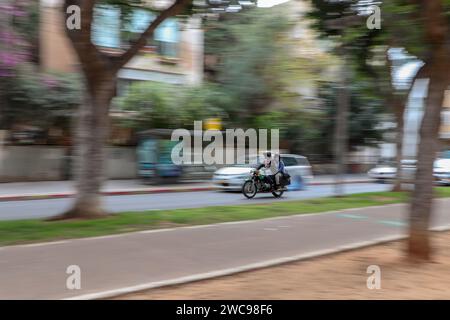 A couple rides a motorcycle between cars. Image in motion on a blurred background Stock Photo