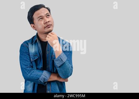 Young Asian Man thinking about question, pensive expression. while hand on chin. On isolated background. Stock Photo