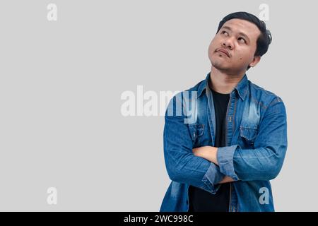 Young Asian Man thinking about question, pensive expression. while hand arms folded. On isolated background Stock Photo