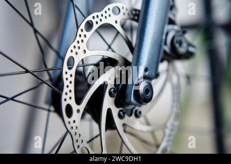 Part of the bicycle's braking system. Grey metal brake disc and brake pads on road bike, close up. Stock Photo