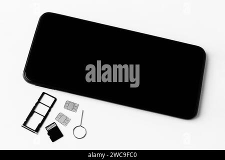 smartphone and open slots for nano SIM cards, two nano SIM cards, micro SD drive and metal key, black and white photo Stock Photo