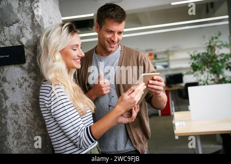 Two young businesspeople using a digital tablet while standing in a boardroom. Stock Photo