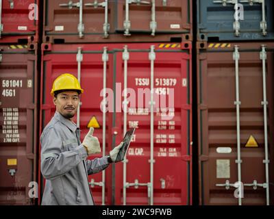 Portrait of Asian male worker wearing safety helmet working in container cargo freight ship for Logistic Import Export . Asian male worker showing thu Stock Photo