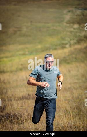 Sporty man actively descends from the mountain, feeling adrenaline and freedom of movement Stock Photo