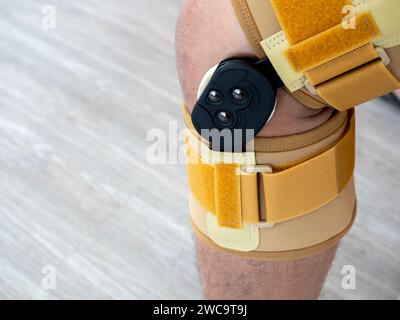 Close up yellow medical standard adjustable stabilised knee brace was worn on the knee of person, man who had injured his leg after playing sports. Stock Photo