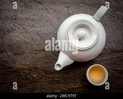 Teapots set. White traditional ceramic teapot with hot tea water cups preparing on old vintage wooden table background with copy space. Stock Photo