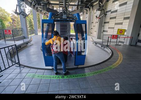 A tourist family gets on one of the cable cars going up the mountain to the amusement park area of Koke Tobe. In Almaty, Kazakhstan. Stock Photo