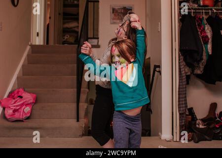 silly siblings dancing in living room with marker on faces Stock Photo