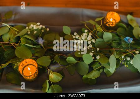 Table setting of eucalyptus leaves and candles on a table runner Stock Photo