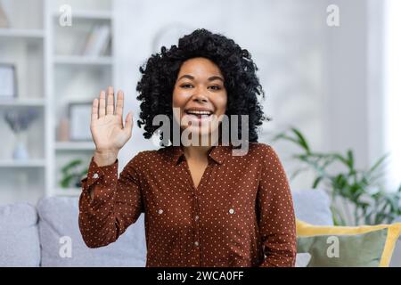 Close-up portrait of a young African American woman greeting, waving and talking to the camera. Stock Photo