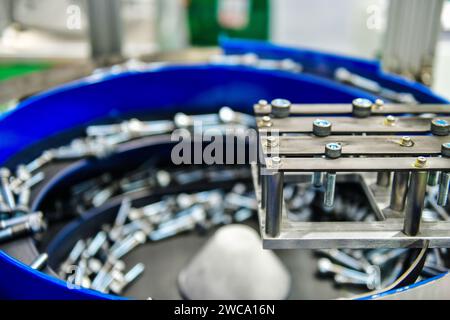 Many small bolts screw and nuts on work piece feederby manufacturing process in factory Stock Photo