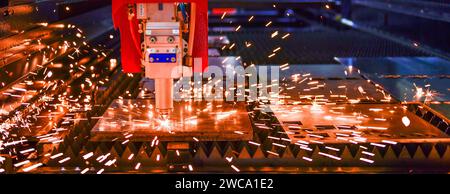 Industrial laser cut machine while cutting the sheet metal with the sparking light. Stock Photo