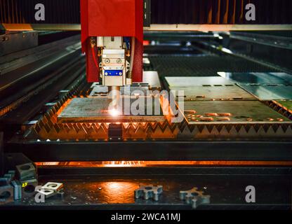 Industrial laser cut machine while cutting the sheet metal with the sparking light. Stock Photo
