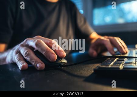 Closeup of male hands using computer mouse at home office desk, freelancer working from home. Selective focus. Stock Photo