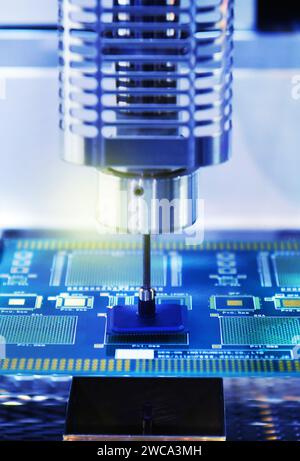 Close up technological process of assembly chip components on pcb board. Automated machine inside at industrial Stock Photo