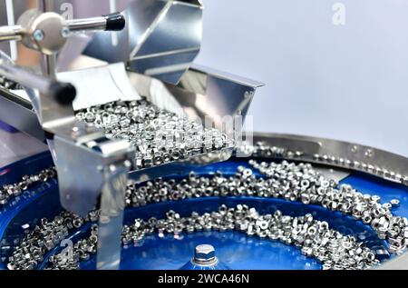 Many small bolts and nuts by manufacturing process in factory Stock Photo